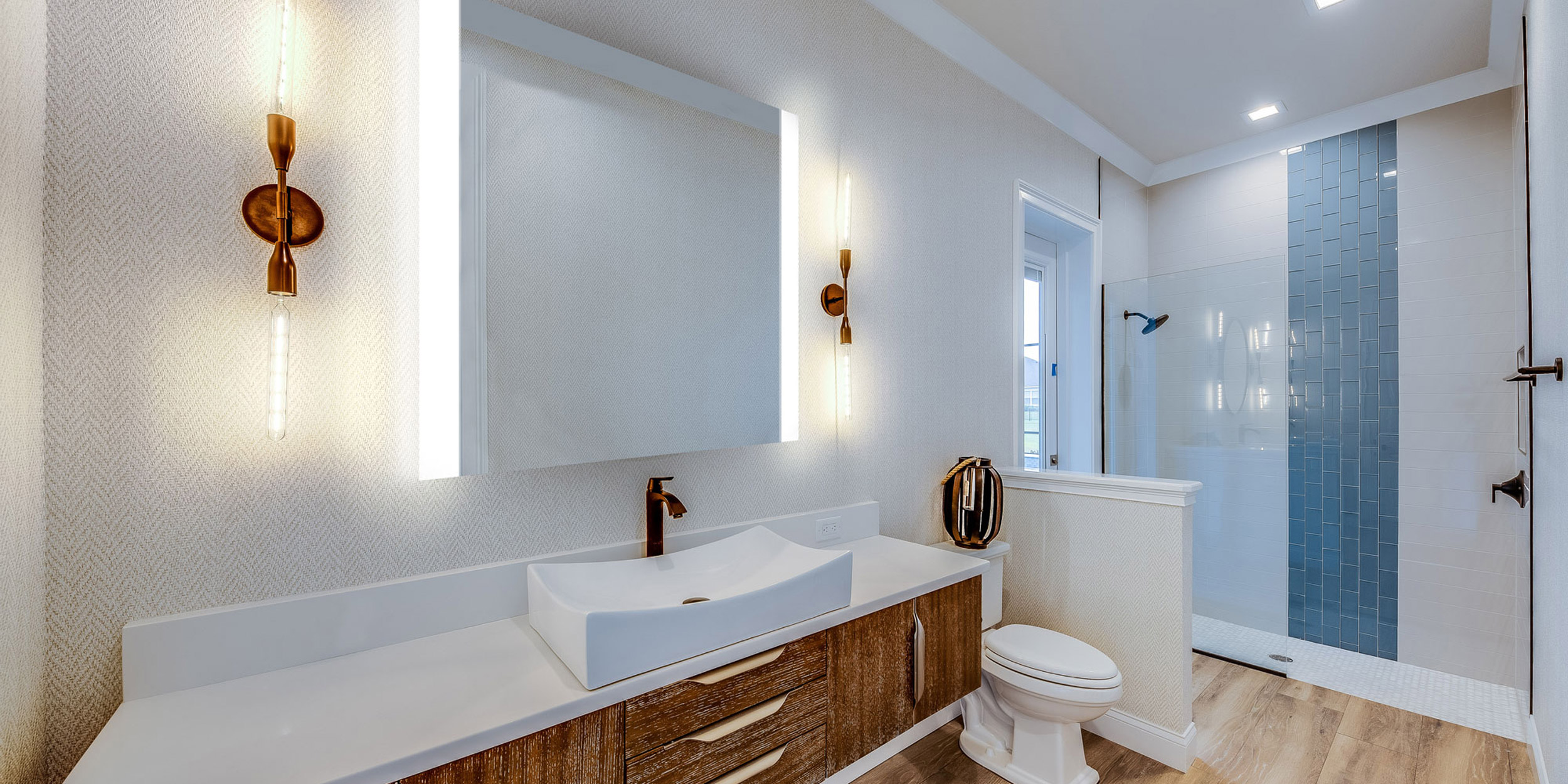 Modern bathroom with a sleek vanity, Seura illuminated mirrors, and a walk-in shower.
