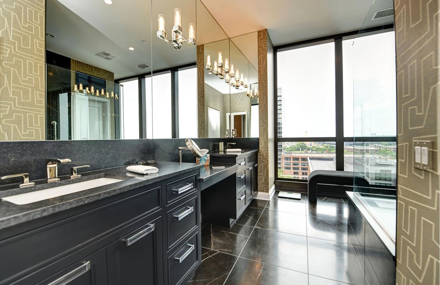 A modern bathroom with black cabinetry, large mirrors, and expansive windows offering city views.