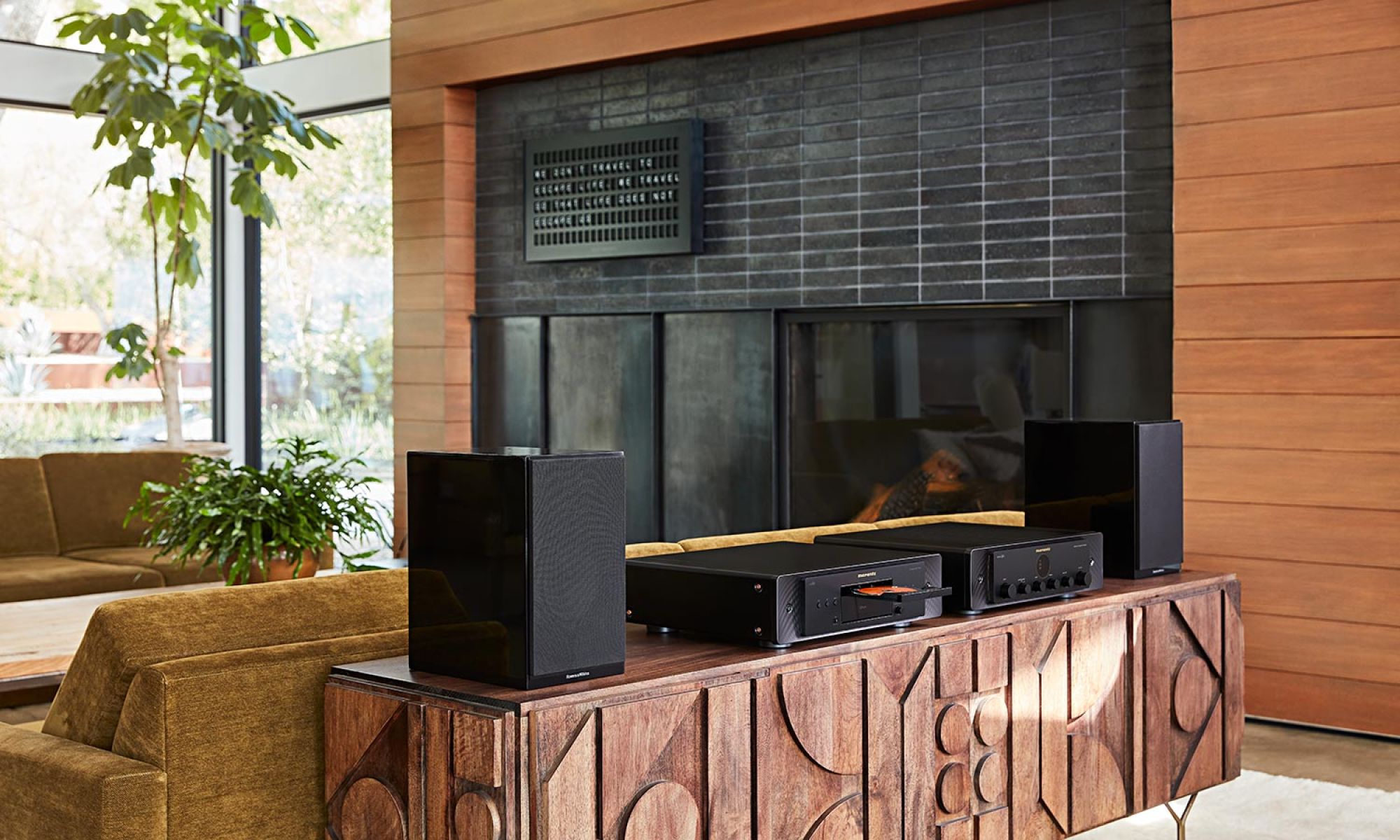 A stylish living room with Marantz audio equipment on a wooden console and large windows letting in natural light.