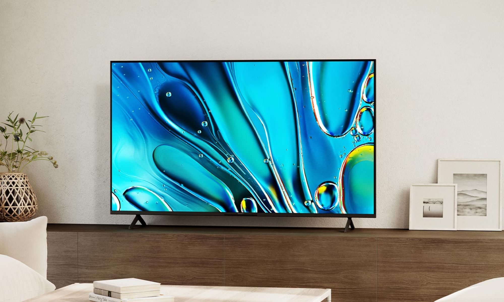 A Sony Bravia 3 flat-screen TV displaying a vibrant abstract image, mounted on a wooden wall in a minimalist living space.