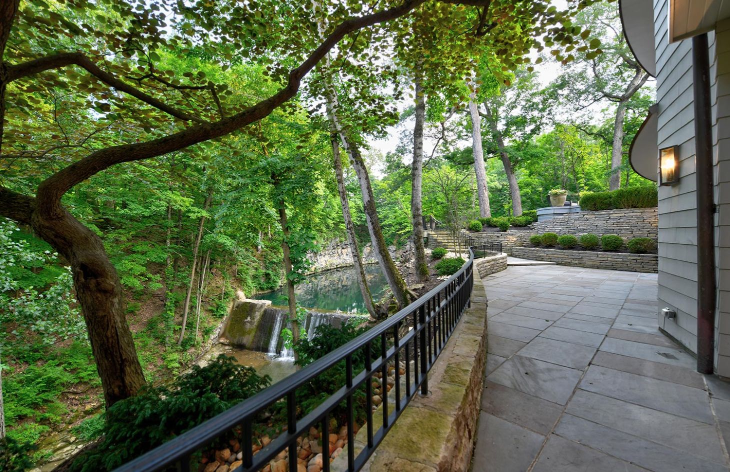 A scenic view of a wooded area with a stone walkway leading to a water feature surrounded by greenery.