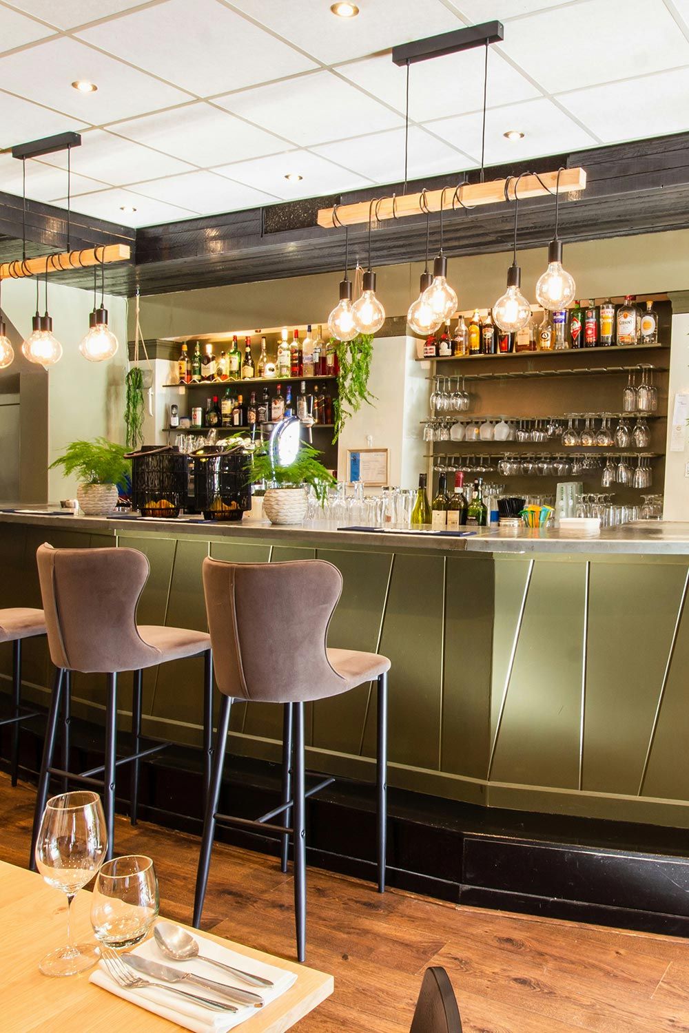 Chic bar with elegant lighting, a well-stocked counter, and comfortable seating.