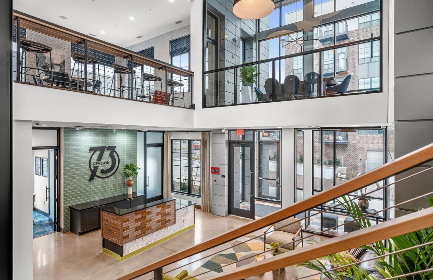 Open and bright lobby space with a reception desk, modern decor, and upper-level seating area.