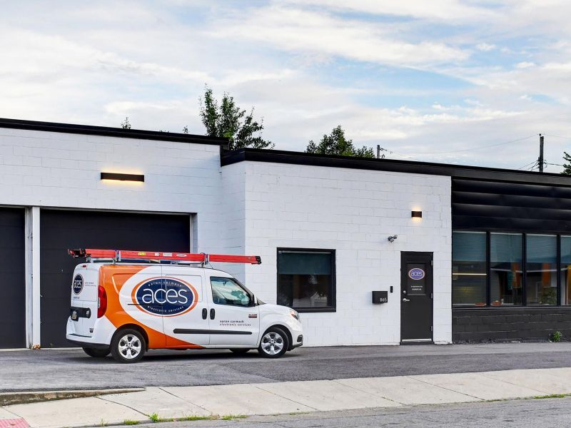 A commercial building with a service van parked in front, showcasing a modern, clean exterior with contrasting black and white walls.