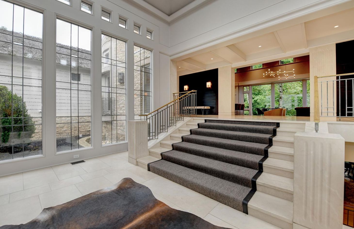 A sophisticated entrance with large windows, carpeted steps, and a view into a spacious lounge area.