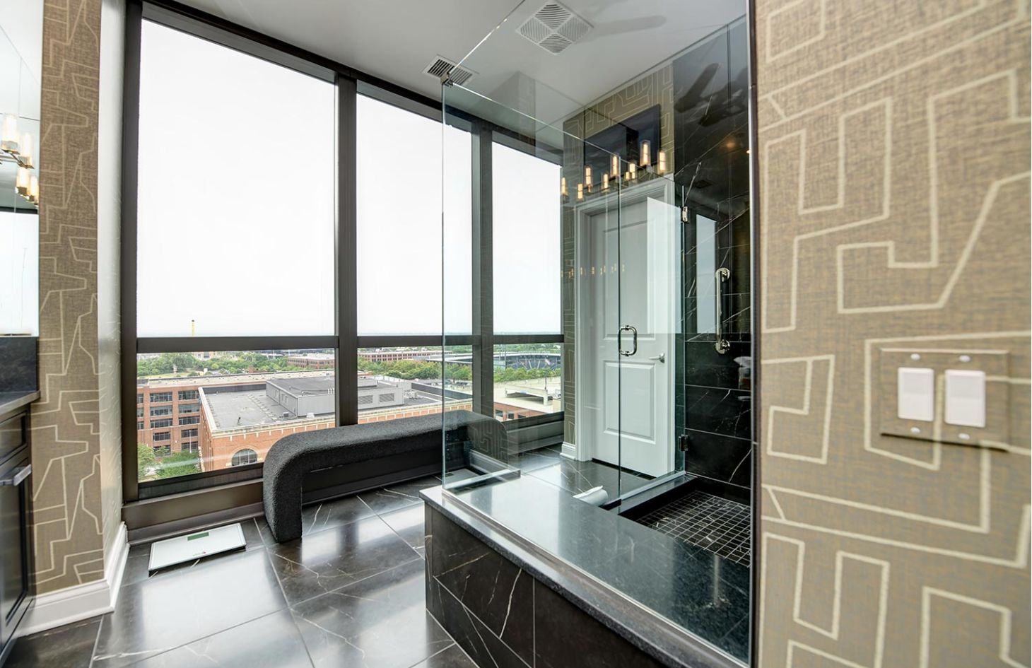 A luxurious bathroom with a black marble shower, large windows, and a modern, minimalistic design.