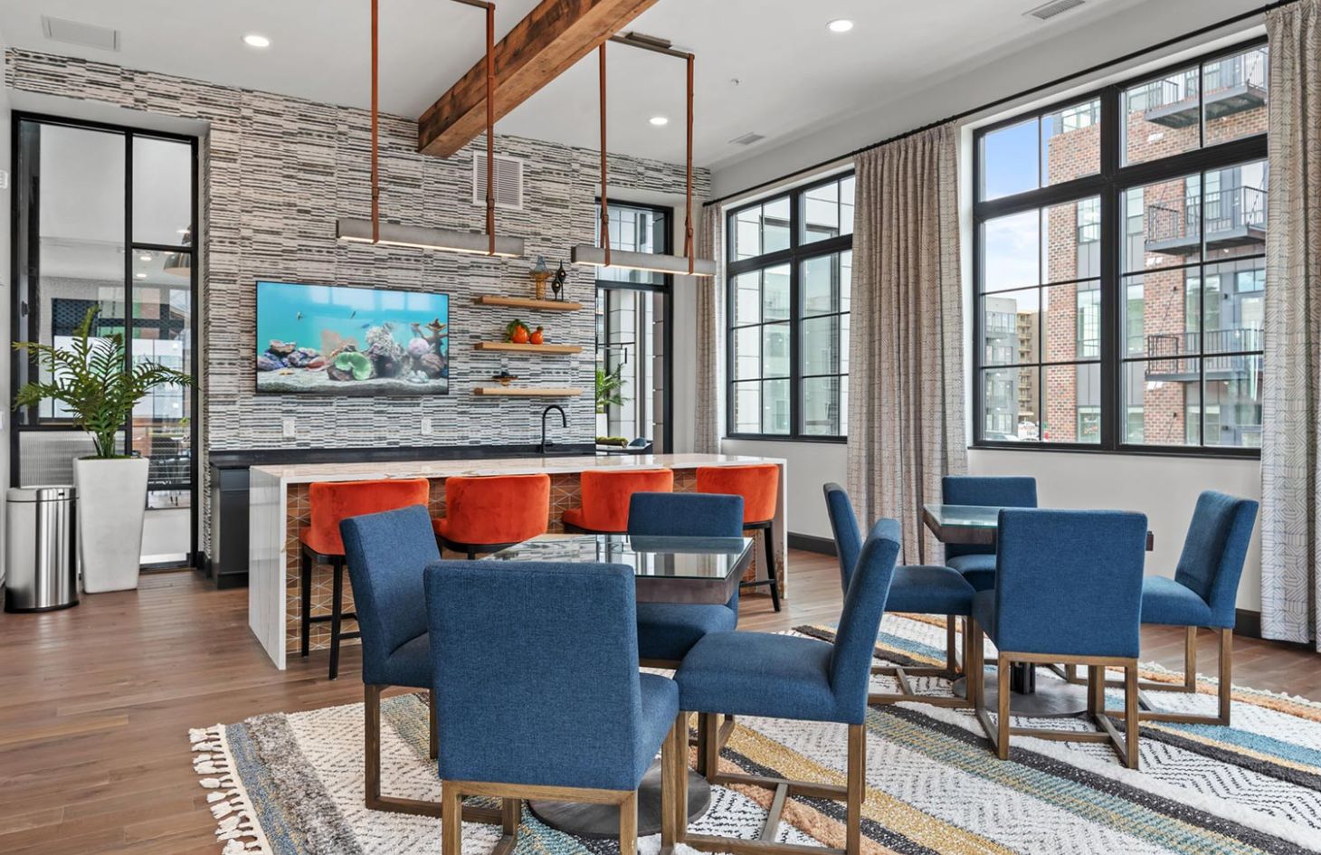 Open dining and lounge area featuring blue and orange seating, large windows, and a wall-mounted fish tank.