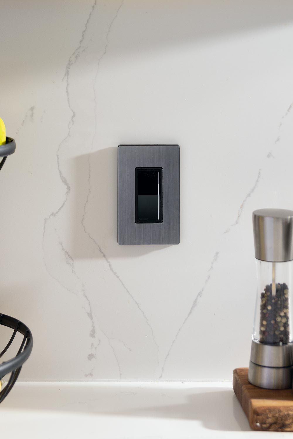 Close-up of a sleek, modern light switch on a marble backsplash.