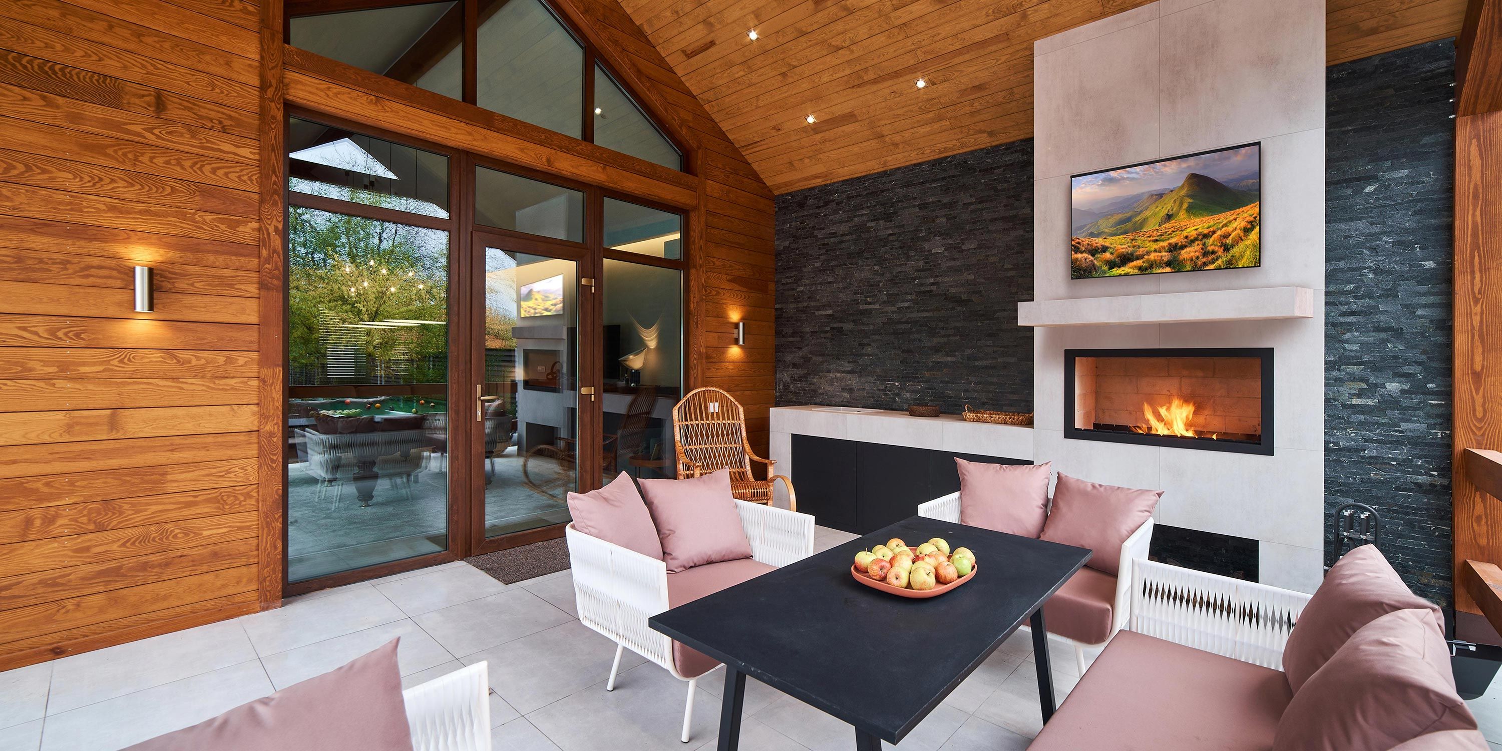 Cozy covered porch with a fireplace, comfortable seating, and a scenic view through large windows.