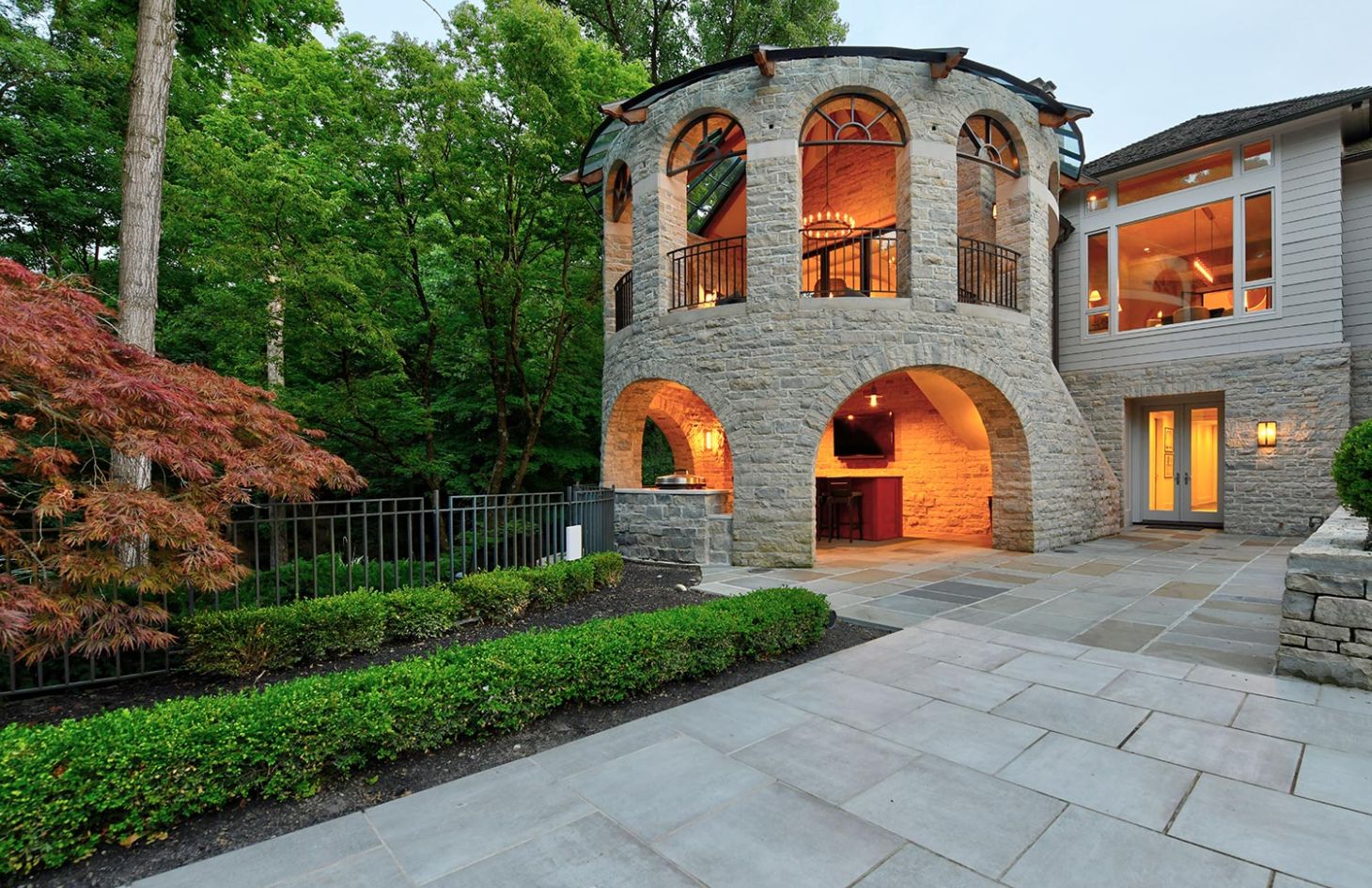 A stone structure with arched openings, outdoor seating, and a view of surrounding trees.