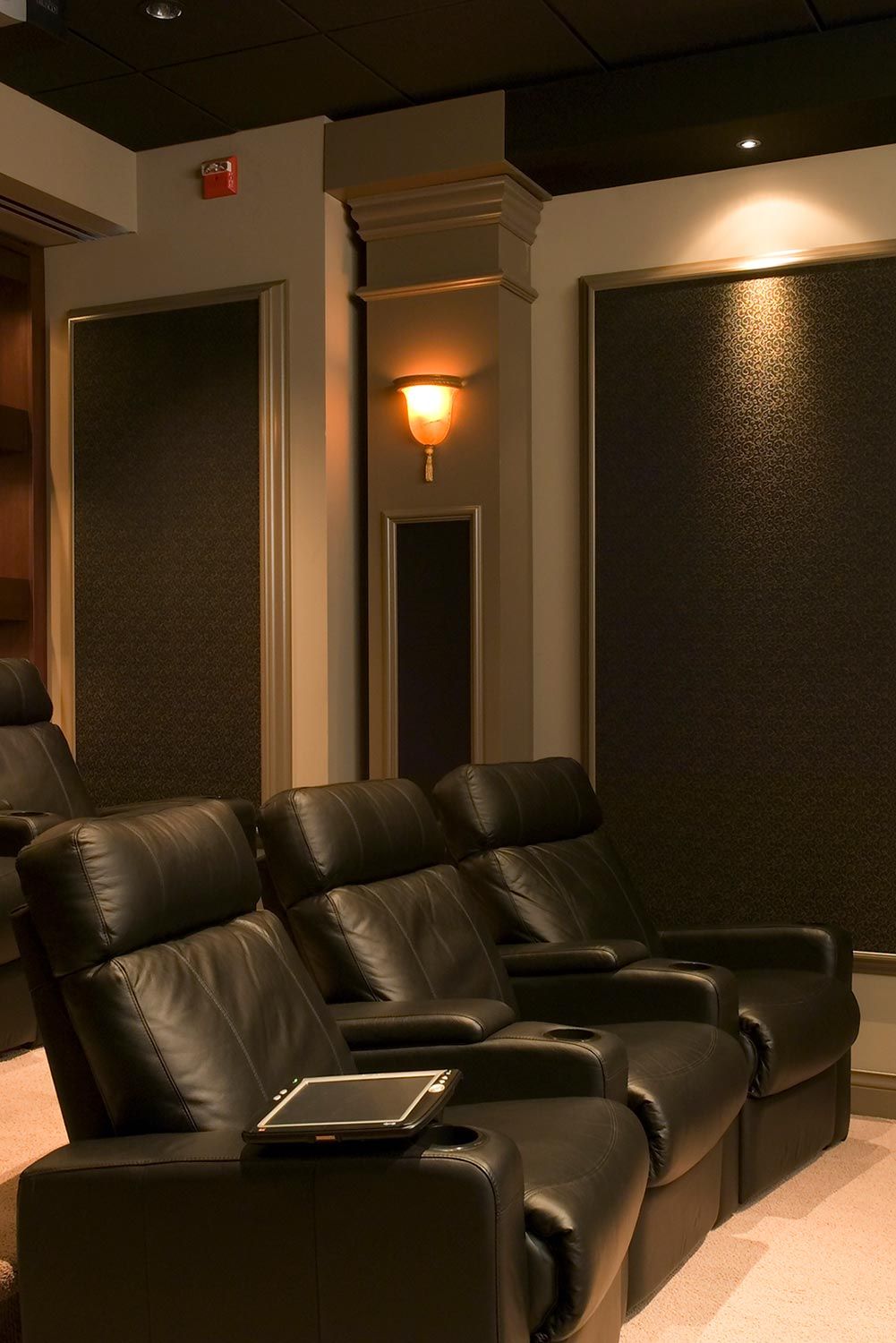 A home theater with black leather recliners and traditional wall sconces, providing a cozy ambiance.