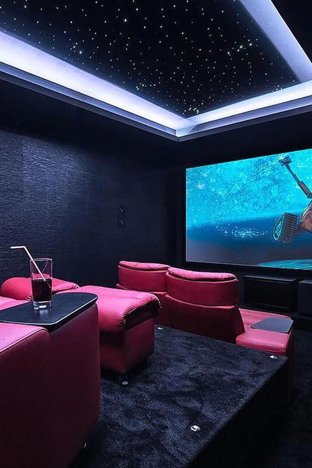 A home theater with red recliners and a ceiling featuring a starry sky effect with LED lights.