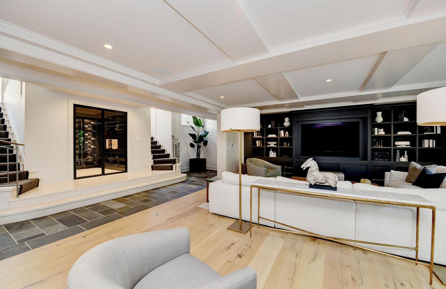 A family room with a large sectional, built-in shelving, and stairs leading to adjacent rooms, creating a welcoming and functional space.